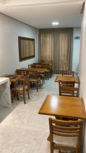 una sala da pranzo con tavoli e sedie in legno di Hotel Goiano a Paranaidji