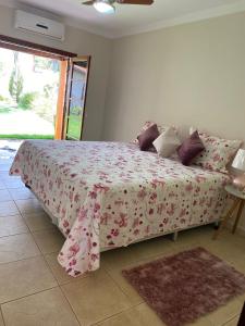 1 Schlafzimmer mit einem Bett mit rosa geblümter Bettdecke in der Unterkunft Espacin Maricris-28 min. Thermas Sao Pedro in Piracicaba