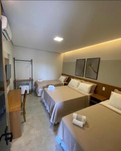 a hotel room with two beds and a television at Hotel Goiano in Estreito
