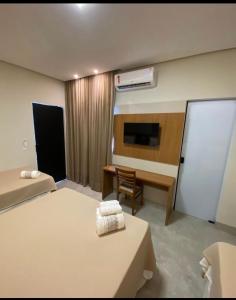 a hotel room with two beds and a desk and a television at Hotel Goiano in Estreito