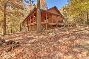 una cabaña de madera en el bosque con bandera en Serenity Woods Cabin with Hot Tub and Fire Pit, en Mountain Home