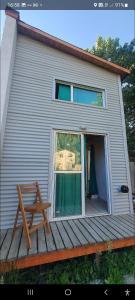 a house with a window and a bench on a deck at Sur tiny house in El Bolsón