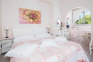 a white bedroom with a bed and a painting on the wall at Beach apartment Demi in Split