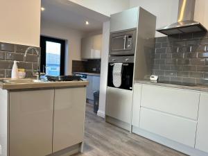 a kitchen with white cabinets and stainless steel appliances at Belsay 4 bedroom bungalow with loft conversion in Horden