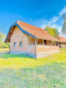 Bosansko Petrovo Selo的住宿－Vikend na Ozrenu，一块砖砌的建筑,在田野上有一个红色的屋顶