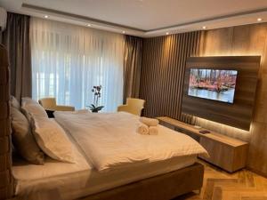 una camera da letto con un grande letto bianco e una televisione di Perla Lux apartmani a Inđija