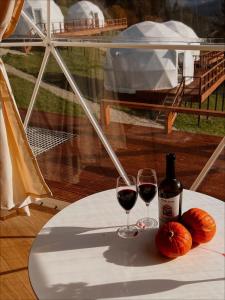 a table with two glasses of red wine and pumpkins at Глемпінг Де Вайб (devibe-vorokhta) in Vorokhta