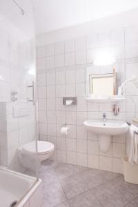 a white bathroom with a toilet and a sink at TM Hotel Dortmund Airport in Holzwickede