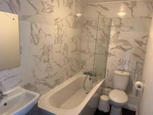 a bathroom with a tub and a toilet and a sink at Beautiful 4 bedroom home 3 bathrooms, Excellent location, Family, Group, Corporate, Contractor in Thamesmead