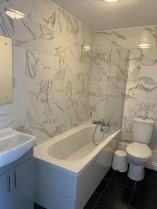a bathroom with a tub and a toilet and a sink at Beautiful 4 bedroom home 3 bathrooms, Excellent location, Family, Group, Corporate, Contractor in Thamesmead