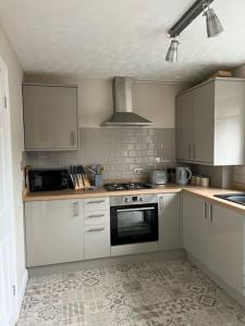 a kitchen with white cabinets and a stove top oven at Mews house 5 minutes walk from the sea in Cleethorpes
