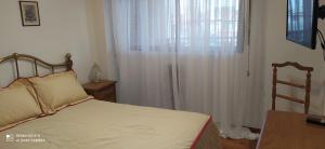 a bedroom with a bed and a window with white curtains at Coiron in Puerto Madryn