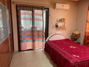 a bedroom with a red bed and a window at Santy in Larnaca