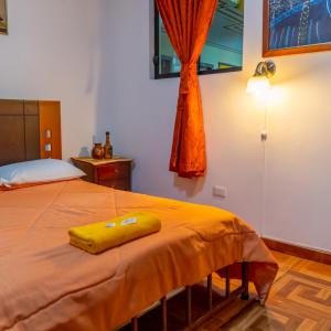 a bedroom with a bed with a yellow towel on it at Mashy´s Hostal in Otavalo