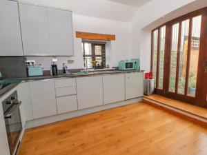 a kitchen with white cabinets and a wooden floor at Burnt Oak Stables in Mold