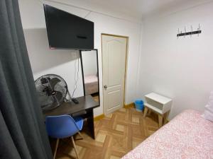 a bedroom with a bed, desk and television at Hostal Familiar S&G in Santiago