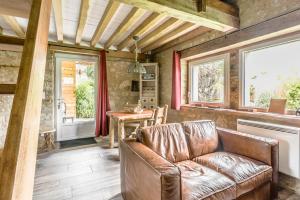 a living room with a leather couch and a table at Gîte La Boulangerie de La Trigalle avec SPA privé in Valognes