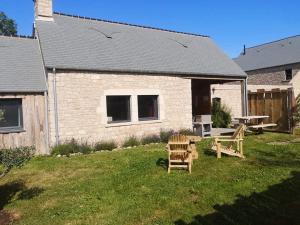 a backyard with two wooden chairs and a picnic table at Gîte La Boulangerie de La Trigalle avec SPA privé in Valognes