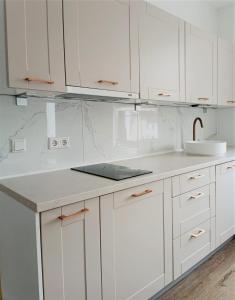 een witte keuken met witte kasten en een wastafel bij Gallery Apartment Bielefeld in Bielefeld