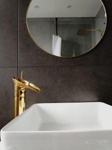 ein Waschbecken mit einem goldenen Wasserhahn und einem Spiegel in der Unterkunft Gallery Apartment Bielefeld in Bielefeld