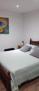 a bed in a bedroom with a painting on the wall at Casa vacaciones Camet Norte in Camet Norte
