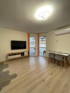 ein Wohnzimmer mit Flachbildfernseher und Tisch in der Unterkunft Barceló Apartment Velingrad in Welingrad