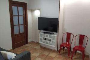 a living room with two red chairs and a flat screen tv at La Casa de los Patos in Toledo