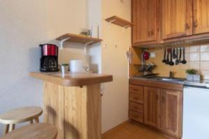 a kitchen with wooden cabinets and a counter with a refrigerator at LA CANELA - Saint Lary Soulan -Pla d'Adet Ski in Saint-Lary-Soulan