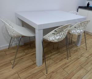 Biały stół i dwa białe krzesła w kuchni w obiekcie Apartament Różana Piątka w Kutnie