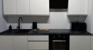 uma cozinha com armários brancos e um balcão preto em Apartament Różana Piątka em Kutno