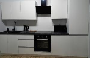 a kitchen with white cabinets and a black oven at Różana Piątka ul Oporowska 22 A in Kutno +19 photos