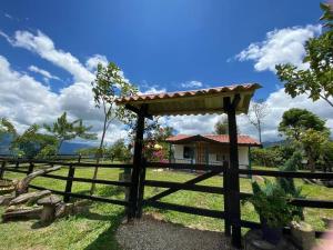 una valla y una puerta con una casa en el fondo en Cabaña Alcaravanes., en San Vicente de Chucurí