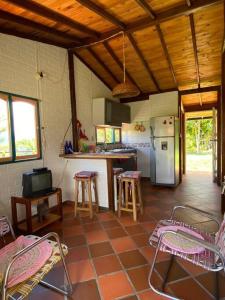 cocina con mesas, sillas y nevera en Cabaña Alcaravanes., en San Vicente de Chucurí