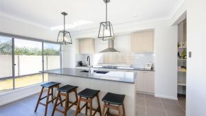 a kitchen with a counter with stools and a sink at Surf and Dunes in Yamba