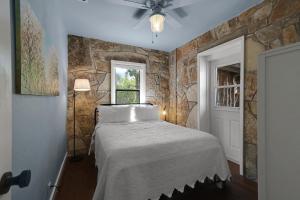 a bedroom with a bed and a stone wall at Milk Bath Springs Cottage in Dripping Springs