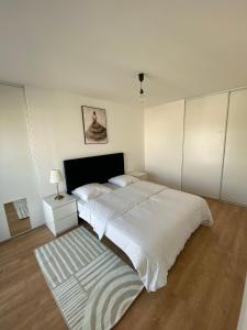 a white bedroom with a large bed and a rug at Luxury appartement 5 Asnières Paris in Asnières-sur-Seine