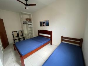 twee bedden in een kamer met blauwe lakens bij Apt 2 suites com ar condicionado e piscina Ubatuba in Ubatuba +9 foto's