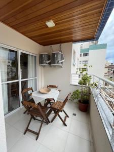 een terras met een tafel en stoelen op een balkon bij Apt 2 suites com ar condicionado e piscina Ubatuba in Ubatuba