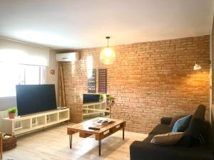 a living room with a brick wall and a television at Adosado para familias al lado de la playa, con piscina in Castellón de la Plana