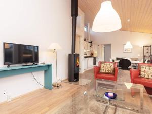 6 person holiday home in Bogense في بوجنسي: غرفة معيشة مع تلفزيون بشاشة مسطحة وكراسي حمراء