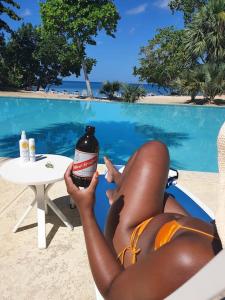 a woman in a bathing suit laying on a chair holding a bottle at Townhouse by The Bay, Little Bay Country Club ,Negril in Orange Bay