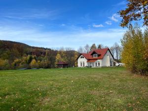 a large white house with a red roof in a field at Dobra1 in Ściegny