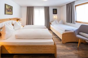 ein Hotelzimmer mit 2 Betten und einem Stuhl in der Unterkunft Villa Daringer in Mayrhofen
