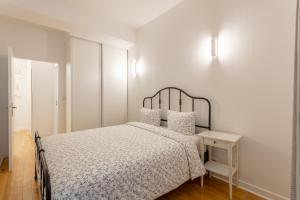 a white bedroom with a bed and a white wall at La Suite à Chatelet in Paris