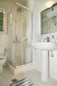 baño blanco con ducha y lavamanos en Windward Suite @ Fiscardo waterfront, en Fiskardho