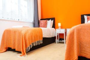a bedroom with two beds with orange walls at Modern Apartment -Ipswich - Great Location in Ipswich