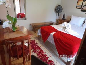 a bedroom with a bed with a red blanket on it at Pousada Campestre Cunha-SP in Cunha