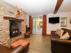 a living room with a stone fireplace and a couch at Garth Morthin The Stables in Morfa Bychan