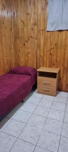 1 dormitorio con 1 cama y pared de madera en PazMaria en Los Antiguos