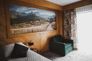 ein Schlafzimmer mit einem Gemälde an der Wand und einem Stuhl in der Unterkunft Willa Koszysta in Bukowina Tatrzańska